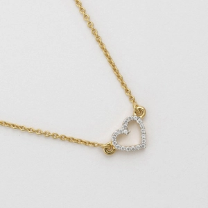 Macro view of gold heart necklace pendant with micro-paved cubic zirconia stones