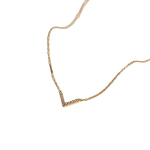 Detailed close-up of a gold V-shaped pendant necklace with shimmering zircon stones