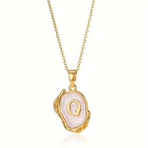 Detailopname van gouden ketting met onregelmatige letter Q hanger en parelmoer inleg