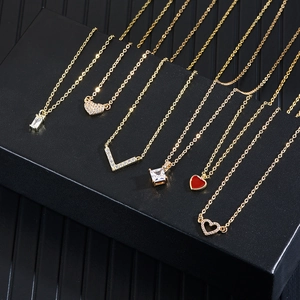 Set of six gold zircon necklaces with diverse geometric pendants on a black luxury display box