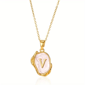 Macro detail van gouden vintage ketting met letter V hanger en parelmoer glans op fijne ketting