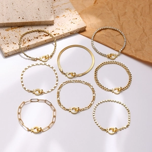 Set de 8 pulseras de cadena dorada con estilo clip y cubano sobre fondo de mármol blanco