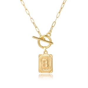 Detail van gouden paperclip ketting met T-sluiting en vierkante hanger met de letter B