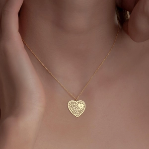 Détail d'un collier doré en forme de cœur avec un pendentif gravé de la lettre A