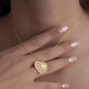 Gros plan d'un collier cœur doré avec gravure de la lettre A sur une chaîne délicate