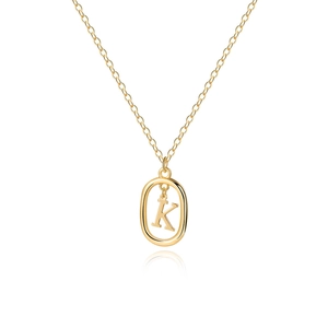 Macro detail of golden oval pendant necklace featuring a minimalist capital letter K design