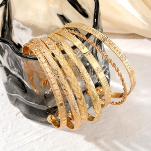 Close-up of golden layered bangles set with twisted and geometric textured patterns