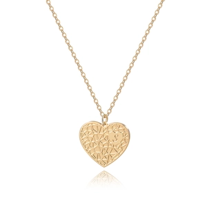 Détail du pendentif cœur doré avec gravure de la lettre S et motif géométrique évidé