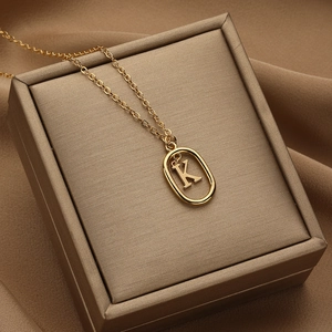18K gold letter K necklace with an oval cutout pendant on a metallic jewelry box