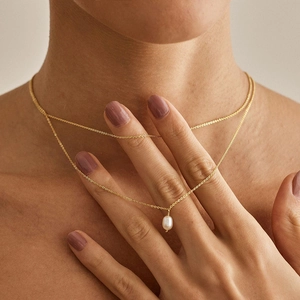 Close-up of double-layer gold necklace with a white pearl pendant on model neck