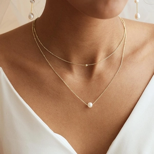 Dettaglio della collana a doppio strato in oro con perle e orecchini coordinati