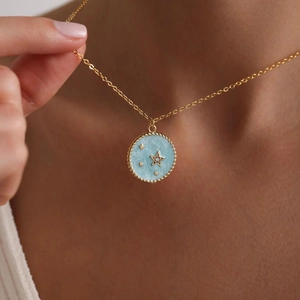 Close-up of gold star pendant necklace with blue marble enamel on a model