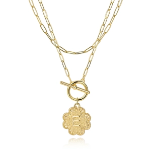 Close-up of golden double layer necklace with clover pendant and letter E detail