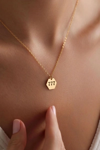 Detailed view of gold angel number 777 pendant necklace on elegant skin tone