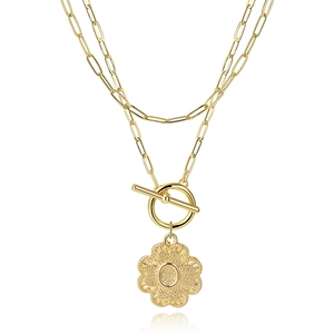 Macro detail of gold paperclip chain necklace with OT toggle clasp and letter O pendant