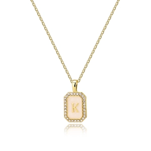 Macro detail of gold octagonal pendant with K initial, zircon border and shell inlay