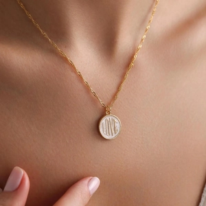 Close-up of a gold LOVE engraved coin pendant necklace on a woman's neck