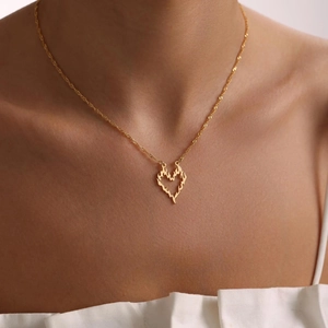 Minimalist gold flame heart pendant necklace shown on female neck with clavicle chain
