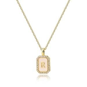 Close-up of golden rectangular pendant with letter R, shell base and zircon crystals