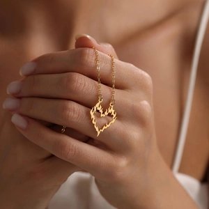 Gold hollow flame heart pendant necklace on female model with minimalist style