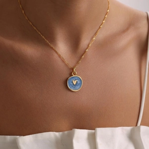 Fashion gold necklace with a blue enamel heart pendant shown on a model neck