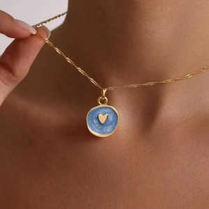 Golden necklace with blue enamel heart pendant shown on neck for a stylish look