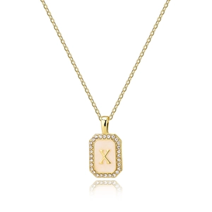 Detailed close-up of golden square pendant with zircon letter X and shell finish