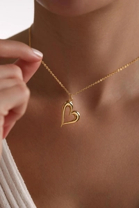 Close-up of asymmetrical hollow heart pendant necklace in gold finish on a model