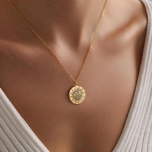 Vintage golden sun face pendant necklace on model wearing white V-neck sweater