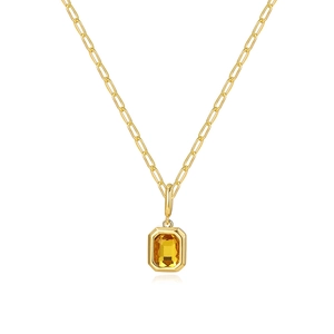 Makroaufnahme einer goldenen Büroklammerkette mit einem smaragdgeschliffenen Bernsteinanhänger