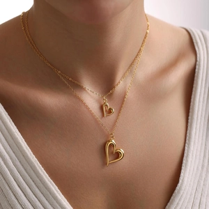 Double-layered gold necklace with two irregular hollow heart pendants on a model