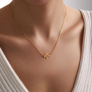 Minimalist gold airplane pendant necklace on model, delicate hollow aircraft jewelry design