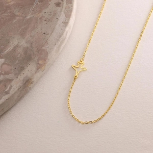 Minimalist gold airplane pendant necklace with a fine cross chain shown at 45 degrees