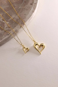Detail view of gold heart pendants on marble tray showing fine link chain and finish