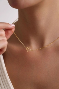 Close-up of minimalist gold-plated airplane pendant necklace worn by a fashion model