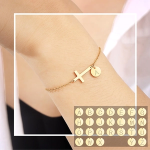 Detail of gold cross bracelet with custom 26 alphabet charms and letter A charm
