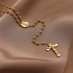 Macro shot of 18K gold plated rosary necklace with cross and Mary medal on silk