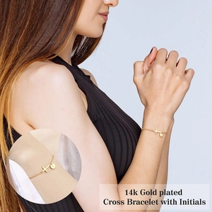 14k gold plated cross bracelet with engraved initial A charm on a female model wrist