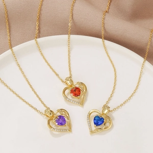 Close-up of 18K gold heart necklaces with rose accent and colorful birthstone gems