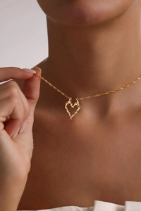 Detail of a gold heart pendant necklace with flame curves on a model's neck