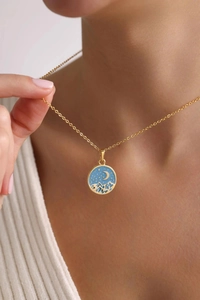 Close-up of golden heart pendant with blue enamel night sky and star on a model