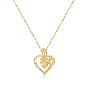 Macro detail of 18K gold heart pendant with yellow gemstone and rose engraving