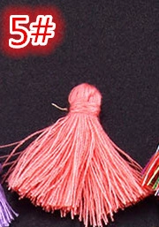 Close-up of pink handmade silk tassel pendant with hanging loop on black texture