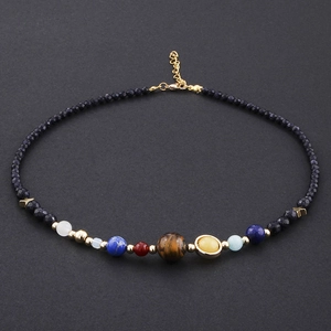 Solar System beaded necklace featuring natural stones and gold stars on a dark background