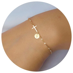 Detailed view of a gold chain bracelet with a cross charm and letter Y engraved pendant