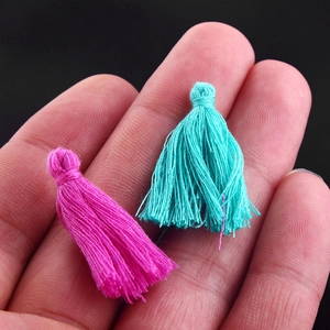 Detailed macro view of mini handmade cotton tassels in rose red and lake blue colors