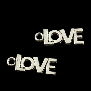 Macro detail of two silver 'LOVE' engraved pendants with polished metallic finish