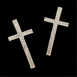 Boucles d'oreilles croix argentées avec cristaux brillants sur un fond noir sobre
