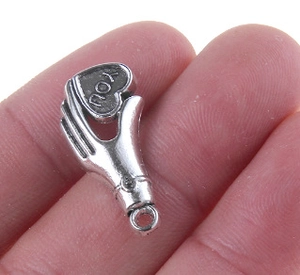 Macro view of silver palm holding heart pendant with YOU engraving for DIY jewelry