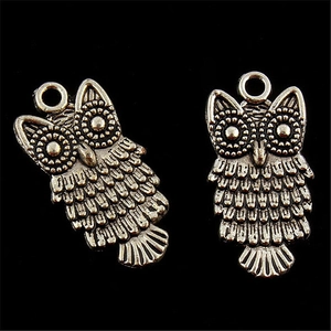 Détail de deux breloques hibou vintage en argent avec textures de plumes pour bijoux DIY